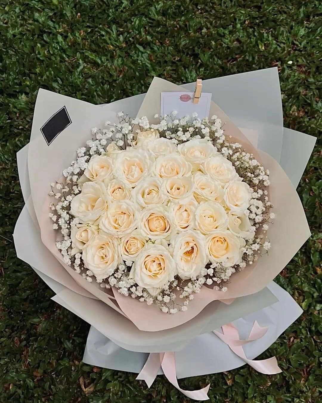 Cream roses ringed with baby's breath, wrapped in sage and blush