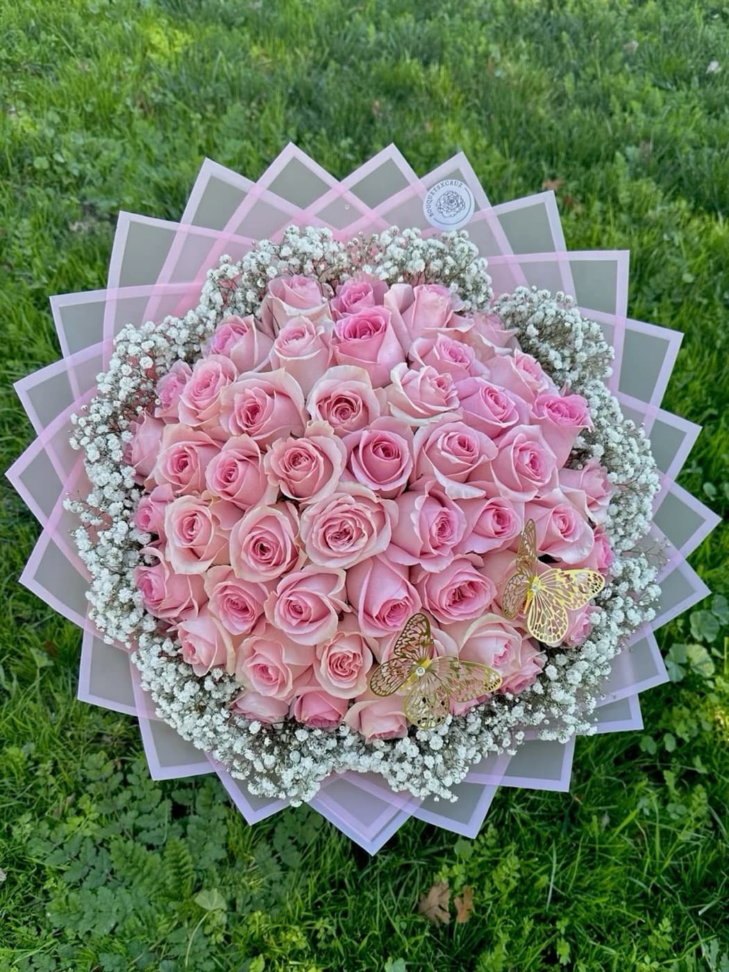 Soft pink roses ringed with baby's breath, two gold butterflies resting on top
